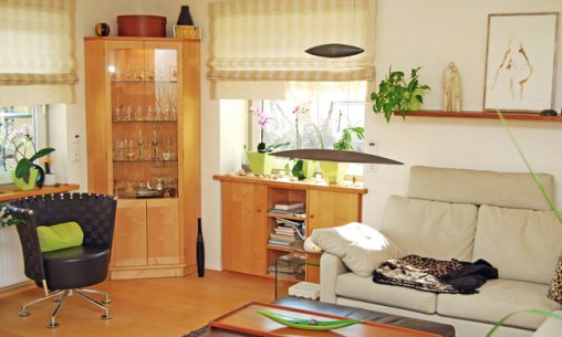 Individuell eingerichtetes Wohnzimmer mit Sideboard und Vitrine aus Naturholz und gemütlichem Ecksofa
