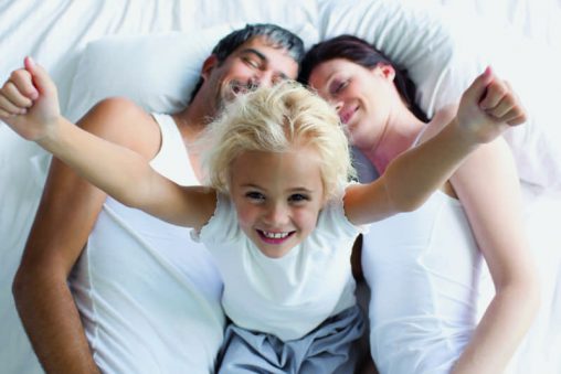 Mädchen mit Ihren Eltern im Bett